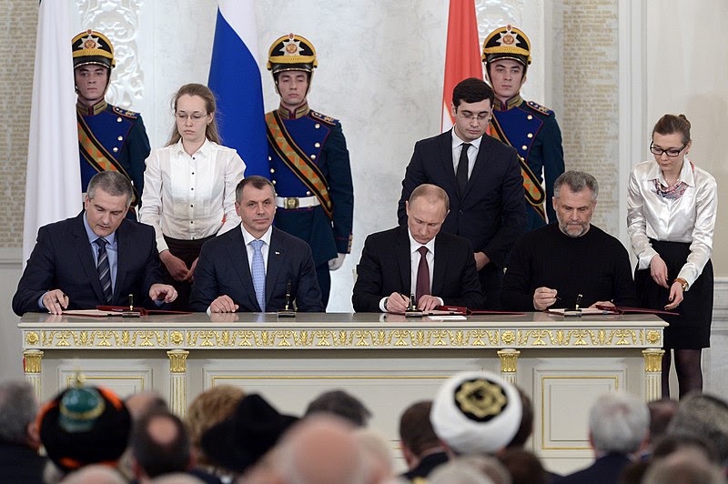 Pictured are Russian President Vladimir Putin and Crimean leaders signing the Treaty of the Ascension of Crimea. Credit: https://commons.wikimedia.org/wiki/Pictured is former Ukranian President Petro Poroshenko.Credit: h